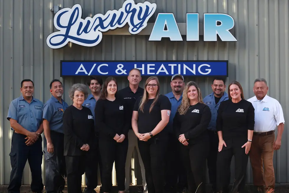 The Luxury Air team standing under the illuminated sign on their Conroe building